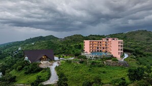 A hotel with a pool, surrounded by lush greenery and hills.
