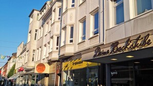Straatbeeld met een gebouw, waar een café genaamd 'Beans Park Coffee' en een winkel met de naam 'Le Jardin' te zien zijn.