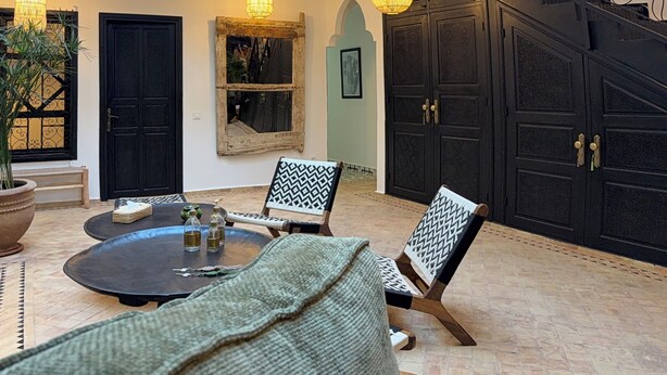 Ein mehrstöckiger Innenhof mit Essbereich, schwarz-weiß gemusterten Stühlen und einem Tisch mit Flaschen.
