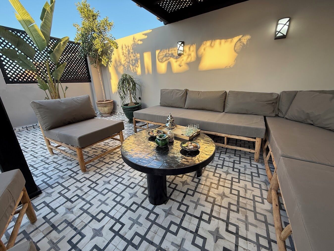 Un patio con una mesa redonda, dos sofás y plantas en macetas.