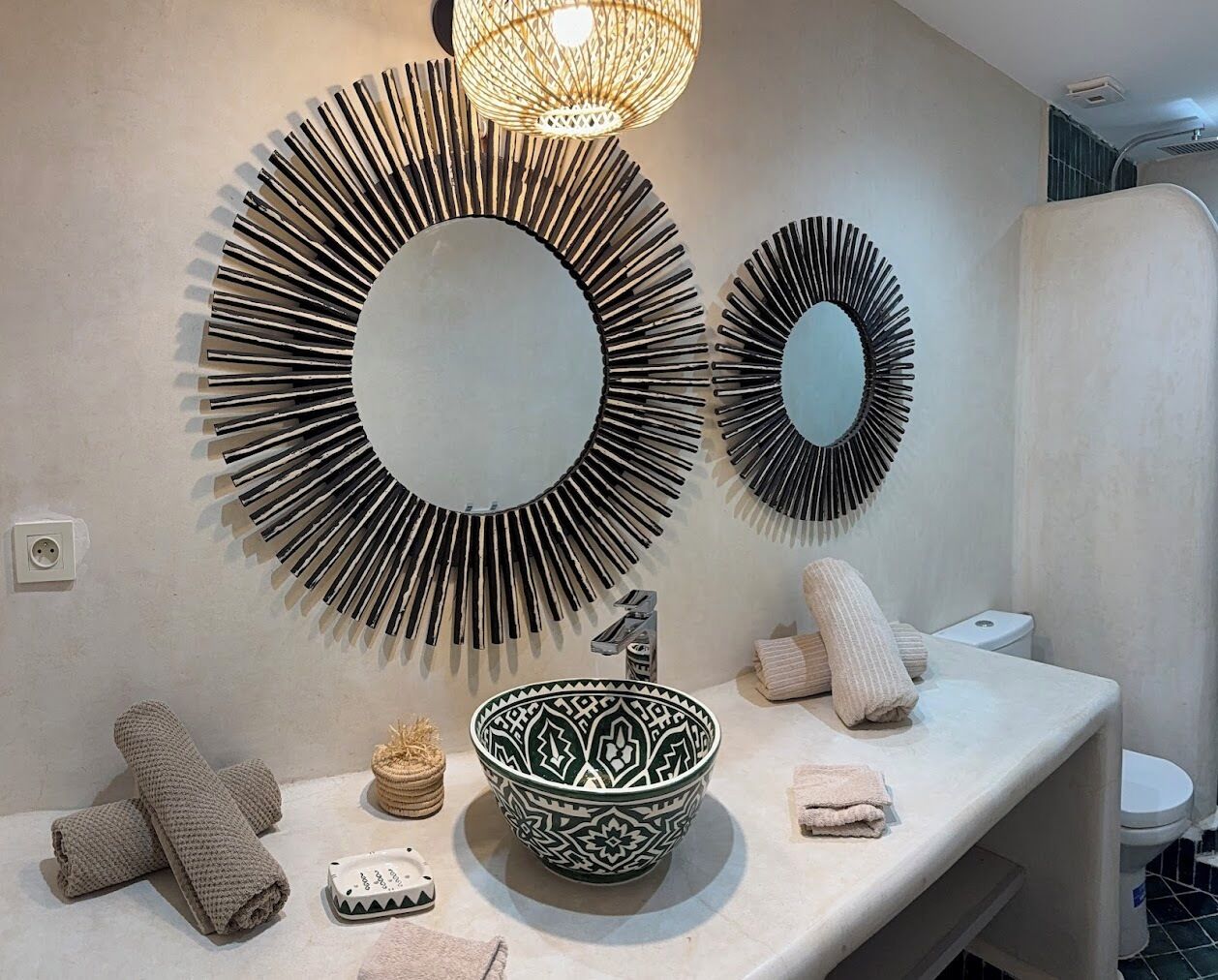Une salle de bain avec un grand miroir, un lavabo sur pied, des serviettes et un luminaire suspendu.