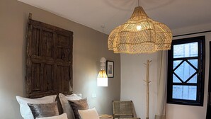 Ein Schlafzimmer mit einem großen Bett, einer gewobenen Leuchte, einem Sessel und einem Fenster mit Blick.
