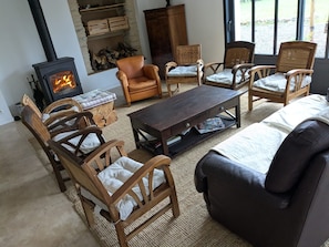 Un salon chaleureux avec une cheminée, des fauteuils en osier, un canapé et une table basse.