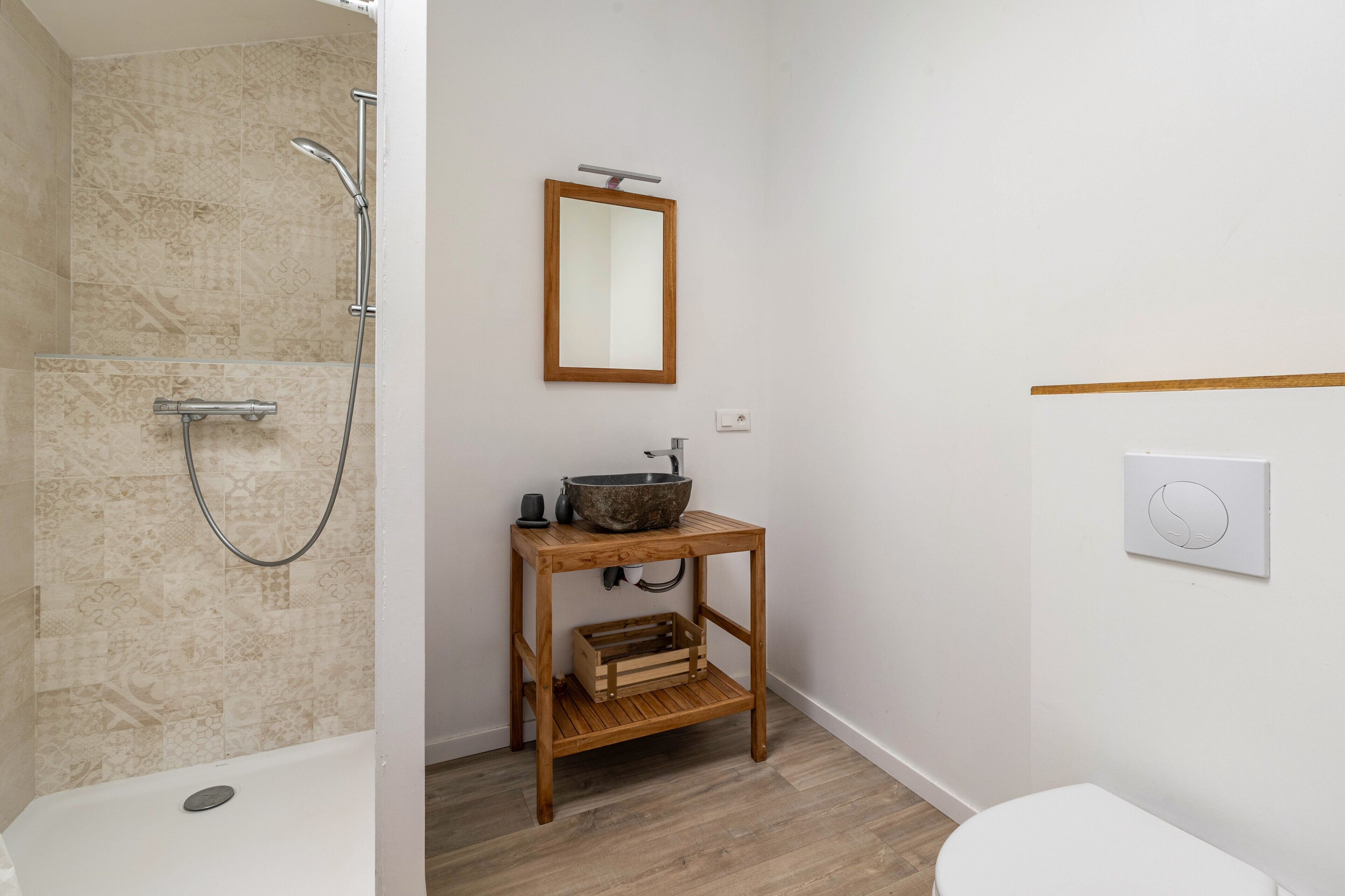 Ein Badezimmer mit Badewanne, Holzwaschtisch mit Waschbecken, Spiegel und Toilette.