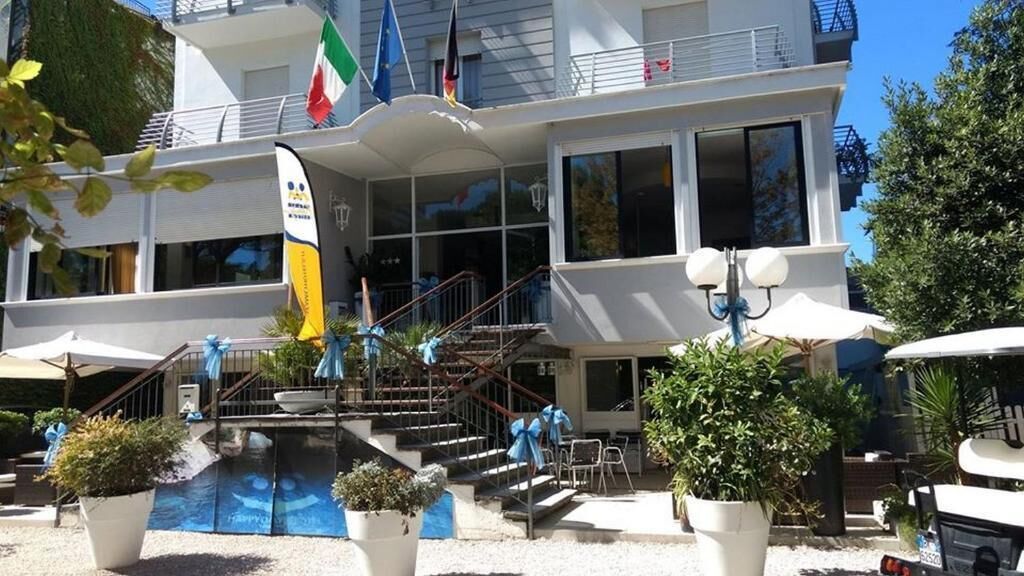 A hotel with a pool, outdoor seating, and multiple flags.