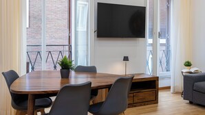 Una sala riunioni moderna con tavolo in legno, sedie nere, una TV a parete e un balcone con vista.
