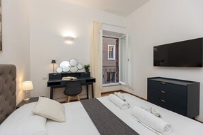 Een hotelkamer met een bed, bureau, stoel, televisie en een raam met uitzicht op een gebouw.