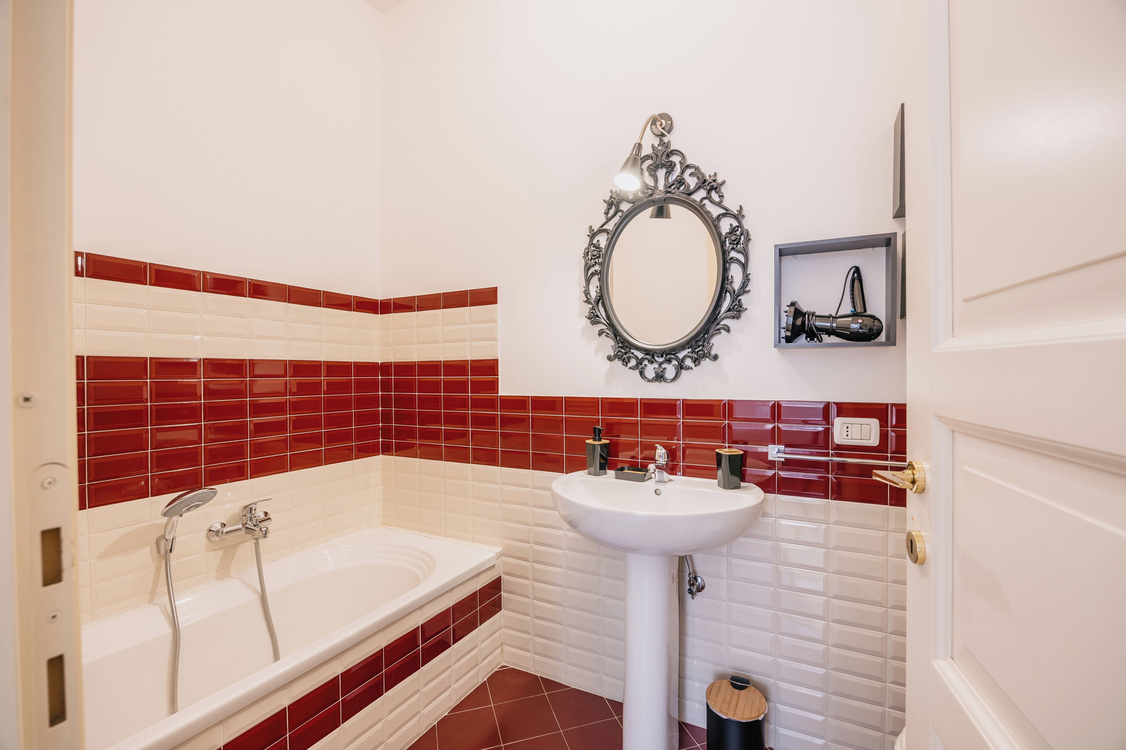 A bathroom with a white bathtub, a white sink, and a mirror with an ornate frame.