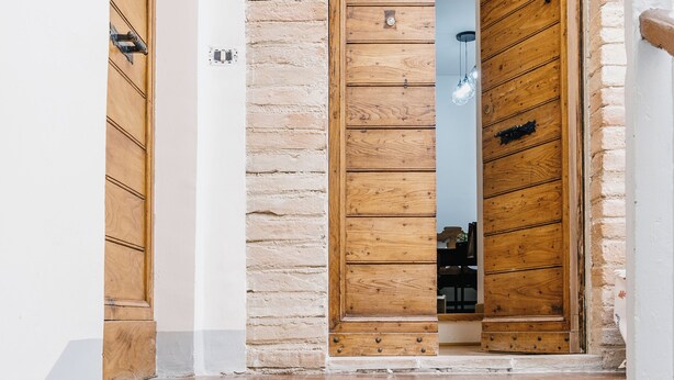 A wooden door with a stone wall, a light fixture above, and a small step leading up to the door. - BHR - The Window on Spoleto (Spoleto)