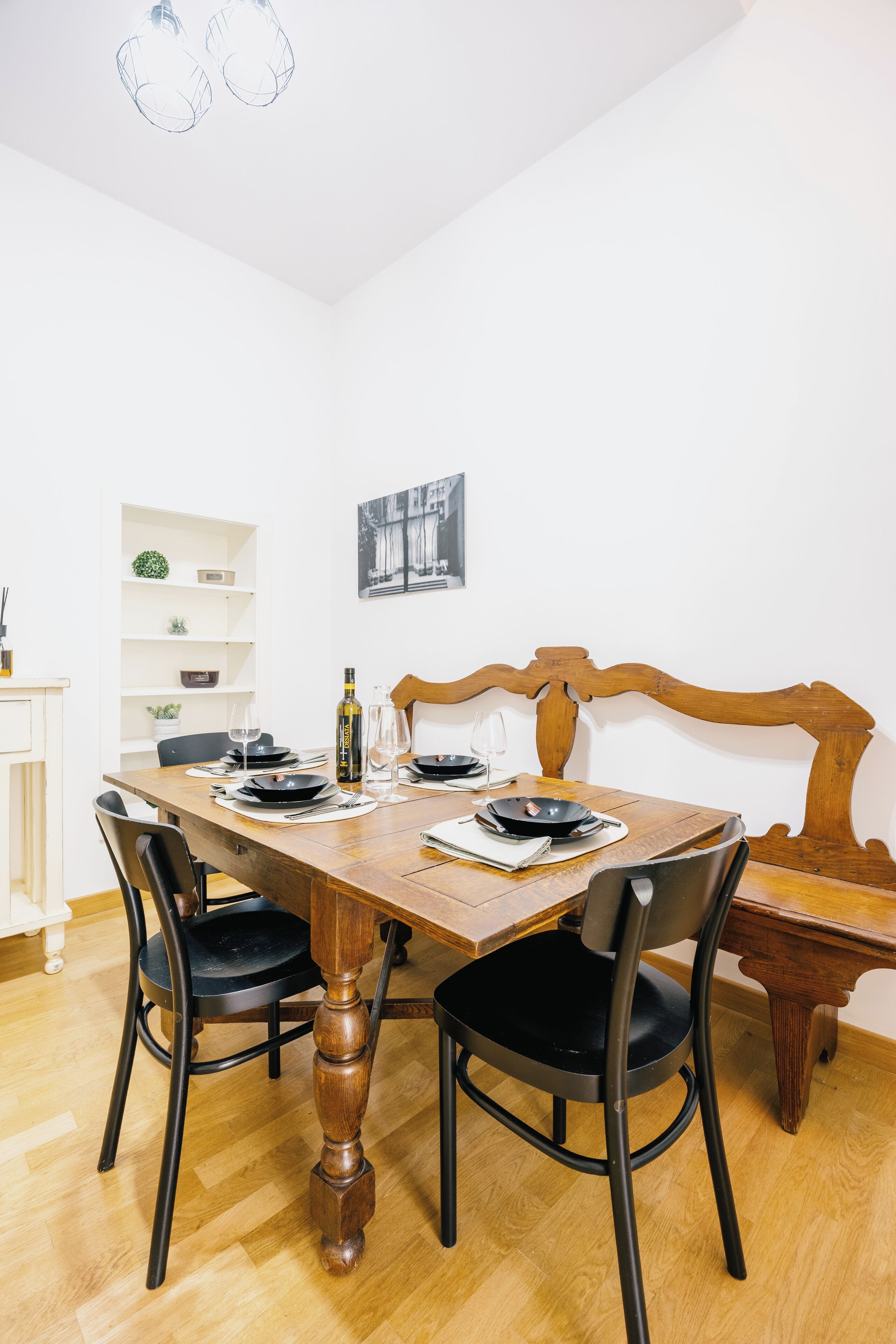 A dining area with a wooden table, black chairs, and a wooden bench.