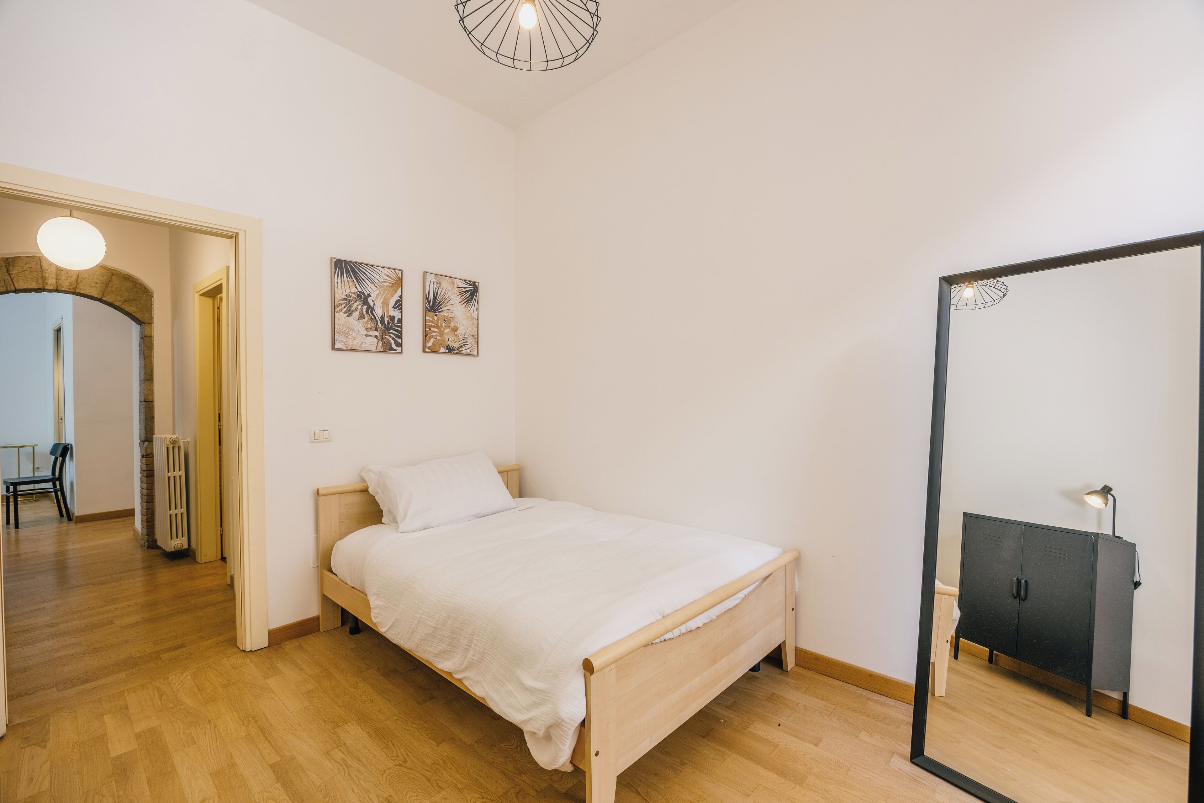 Ein Schlafzimmer mit einem hölzernen Bett, einem schwarzen Kleiderschrank und zwei an der Wand befestigten Kunstwerken.
