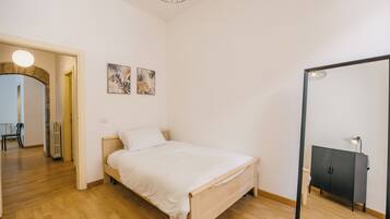 Ein Schlafzimmer mit einem hölzernen Bett, einem schwarzen Kleiderschrank und zwei an der Wand befestigten Kunstwerken.