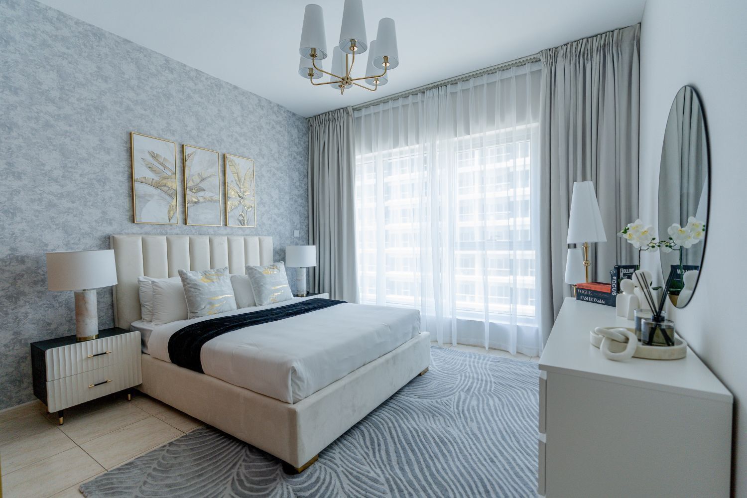 Een moderne slaapkamer met een groot bed, nachtkastjes, een bureau en een spiegel.