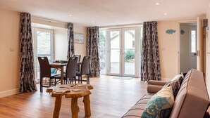 A spacious living area with a wooden dining table, chairs, and a sofa. - Modern ground floor apartment, near the beach (Ceredigion)