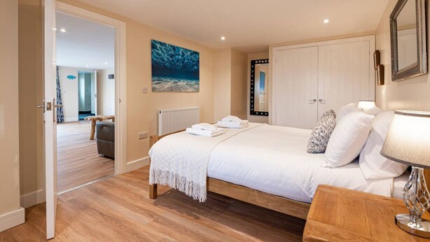 A bedroom with a bed, bedside table, and a mirror. - Modern ground floor apartment, near the beach (Ceredigion)