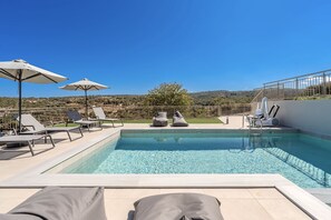 A rooftop pool with clear blue water, surrounded by lounge chairs and umbrellas, offering a view of the countryside. - Villa Allargo - with Private Pool (Gerani)