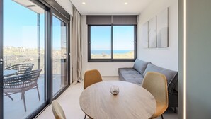 A modern room with a large window, a round table, a sofa, and a balcony with wicker furniture. - Villa Allargo - with Private Pool (Gerani)