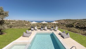 A swimming pool with lounge chairs and umbrellas, surrounded by a grassy area and overlooking a hilly landscape. - Villa Allargo - with Private Pool (Gerani)
