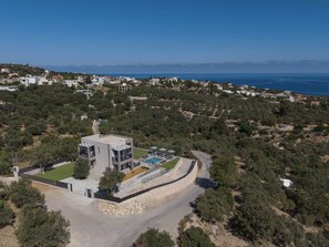 A modern two-story building with a swimming pool, surrounded by dense greenery and a clear view of the sea. - Villa Allargo - with Private Pool (Gerani)