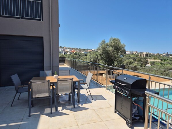A balcony with a table and chairs, a grill, and a view of the surrounding area. - Villa Allargo - with Private Pool (Gerani)