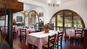Un comedor con mesas cubiertas de manteles rosas, sillas de madera y una araña.