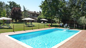 Una piscina rectangular con borde de azulejos, rodeada por un patio de ladrillo.