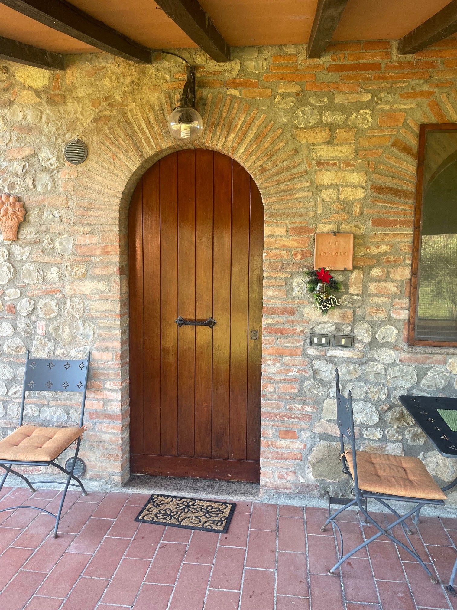 Ingresso con un muro in pietra, una porta in legno, una panchina e una sedia.