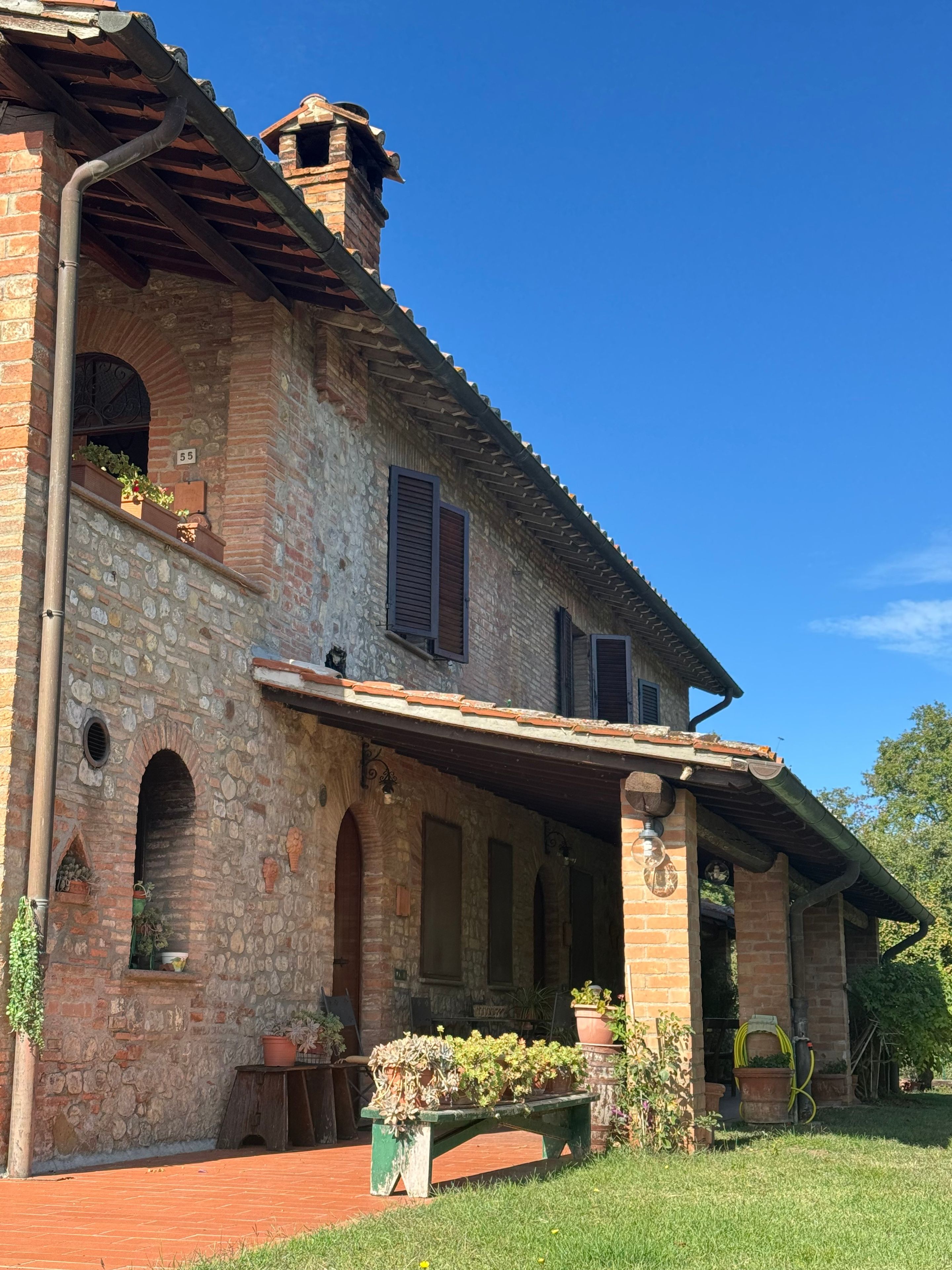 Un edificio de piedra con un porche cubierto, ventanas de arco y una chimenea.