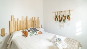 A neatly made bed with a patterned bedspread, a wooden headboard, and a macrame wall hanging. - Cubo's Casa Rural San Cristobal Cortijo el Puntal / rural / communal pool / large outdoor areas / views / free wifi (Teba)