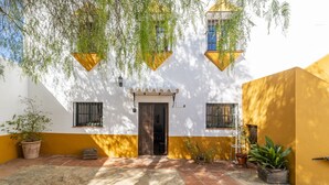 A courtyard with a white building, yellow walls, and a tiled floor. - Cubo's Casa Rural San Cristobal Cortijo el Puntal / rural / communal pool / large outdoor areas / views / free wifi (Teba)