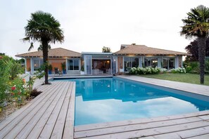 Una casa moderna con piscina, patio y jardín.