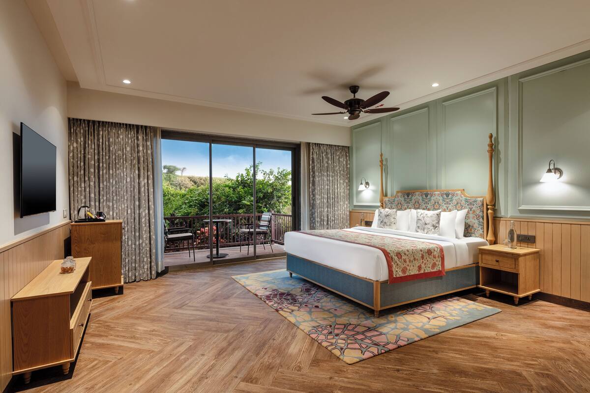 Un dormitorio con una cama grande, muebles de madera, un ventilador de techo y un balcón con vistas.