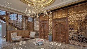 A luxurious lobby with a grand chandelier, ornate wooden doors, and a seating area with patterned chairs. - WelcomHeritage Akashganga Resort & Spa (Bichhiwara)