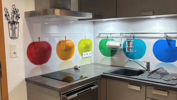 Una cocina moderna con encimera de acero inoxidable, horno empotrado y un fregadero.