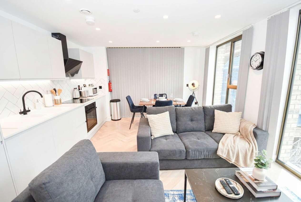 Ein modernes Wohnzimmer mit grauem Sofa, Couchtisch und Essbereich mit Tisch und Stühlen.