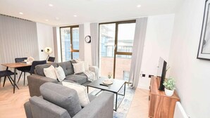 Una sala de estar moderna con sofá, mesa de centro y mueble para televisión.
