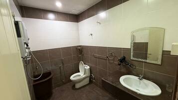 A compact bathroom with a toilet, sink, and shower.