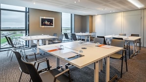 A modern conference room with large windows, white tables, and black chairs. - CDG Airport Terminal Hotel, Paris (Tremblay-en-France)