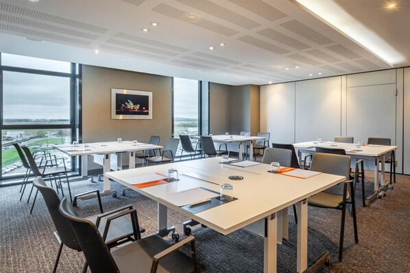 A modern conference room with large windows, white tables, and black chairs. - CDG Airport Terminal Hotel, Paris (Tremblay-en-France)