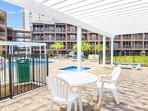 Un espace extérieur abrité comprenant une piscine, des chaises longues et une table.