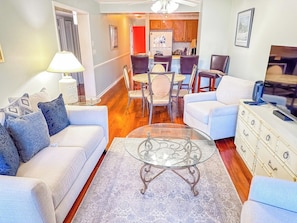 A living room with a glass coffee table, sofas, and a dining area with chairs. - Tilghman Beach and Racquet Club 170 (North Myrtle Beach)