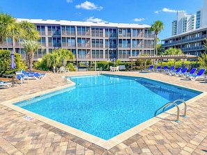 A rectangular swimming pool with a clear blue water surface, surrounded by a tiled deck. - Tilghman Beach and Racquet Club 170 (North Myrtle Beach)