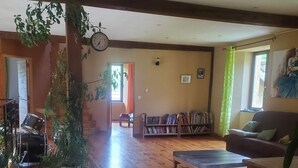 Un salon spacieux avec un plancher en bois, une bibliothèque, un canapé et une batterie.