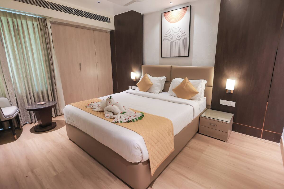 A hotel room with a bed, bedside tables, a chair, and a wall-mounted artwork.