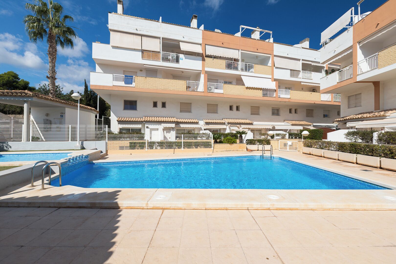 Un immeuble résidentiel doté d’une piscine, de balcons et offrant une vue sur un ciel dégagé.