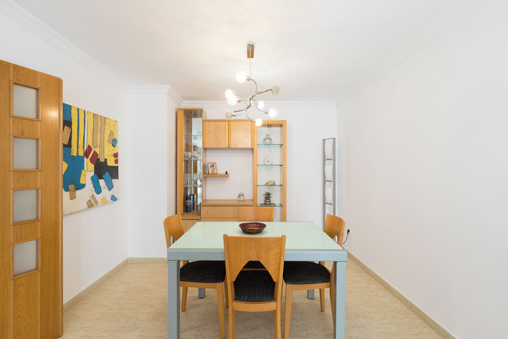 Un comedor con una mesa azul claro, sillas de madera y una araña.