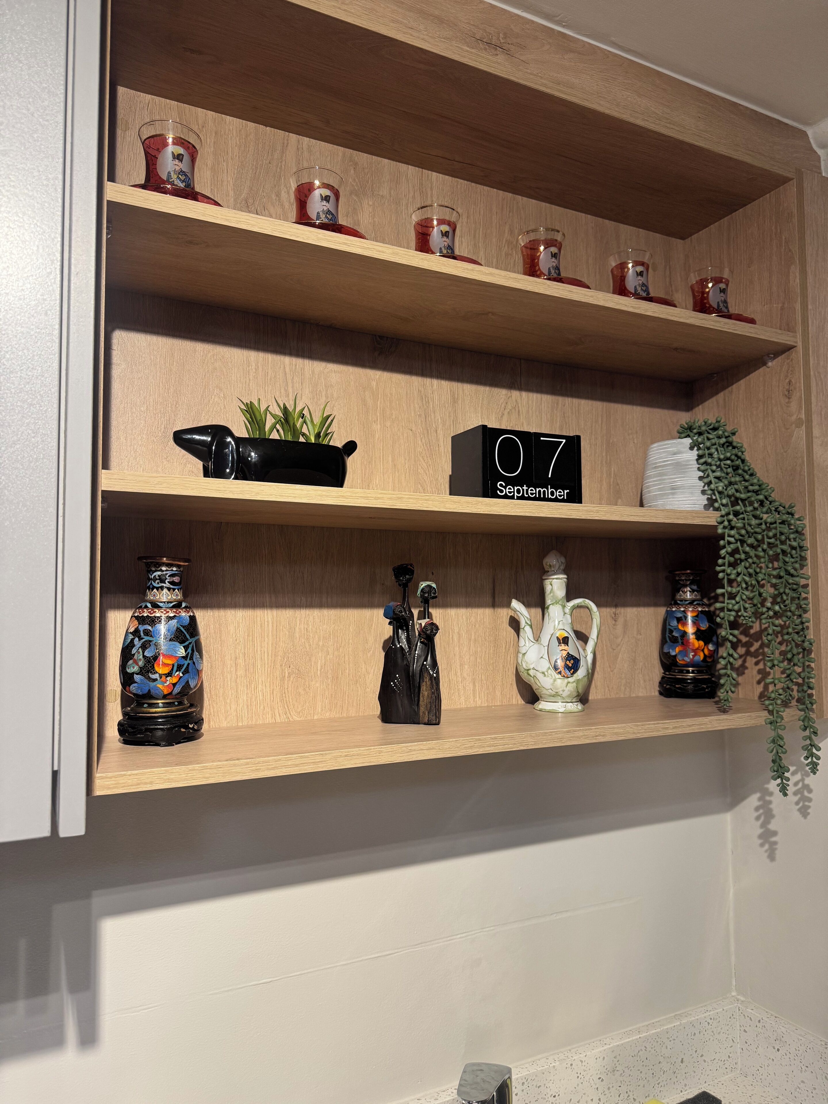 A wooden shelf with decorative items including a clock, vases, and a plant.