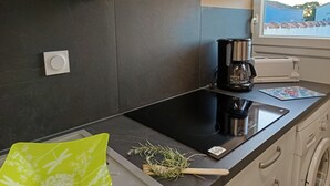 Eine moderne Küche mit einem schwarzen Induktionskochfeld, einer Kaffeemaschine und einer Waschmaschine.