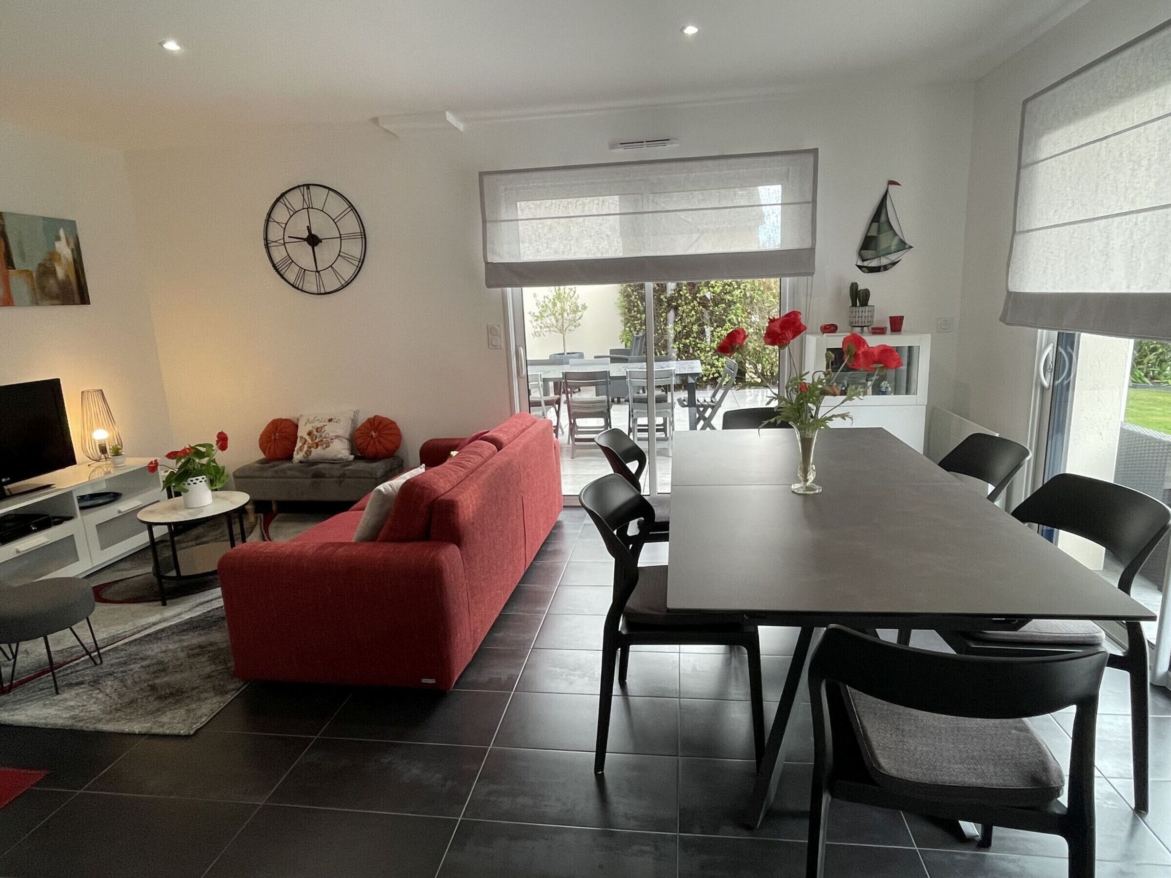 A modern living room with a red sofa, a dining table, and a TV.