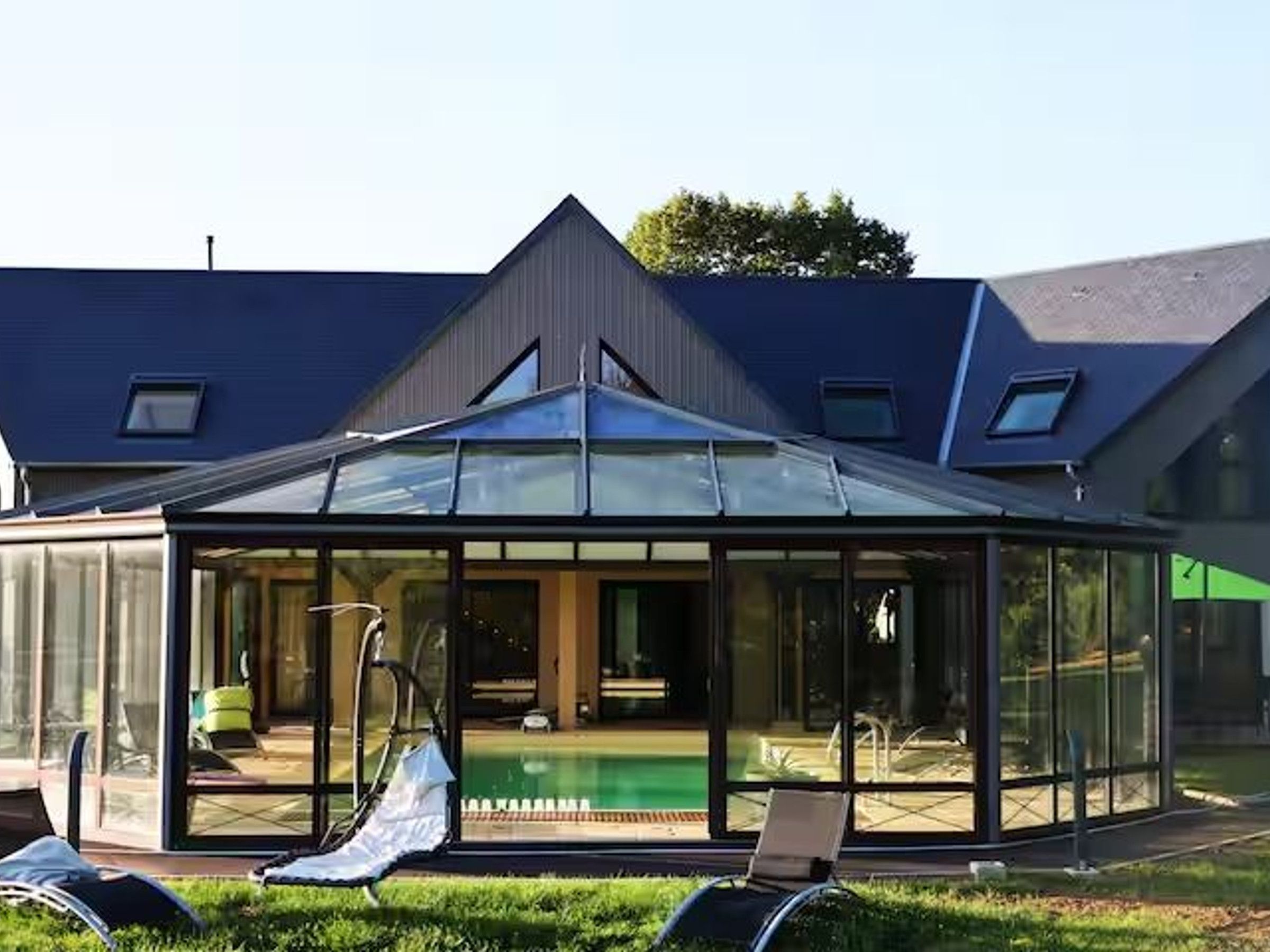 Een modern huis met een glazen patio, een zwembad en een vrij uitzicht op het interieur.